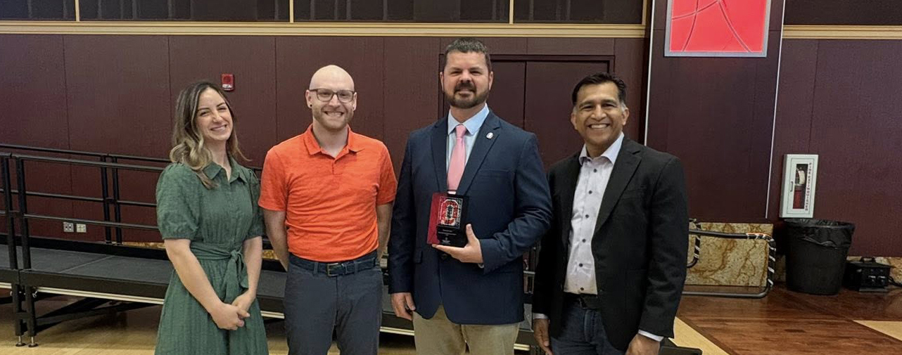 From left, National Registry Research Fellows Kayla Riel, Jacob Kamholz, and Chris Gage, holding the Doctoral Research Award, stand with Dr. Ash Panchal, Research Director at the National Registry.
