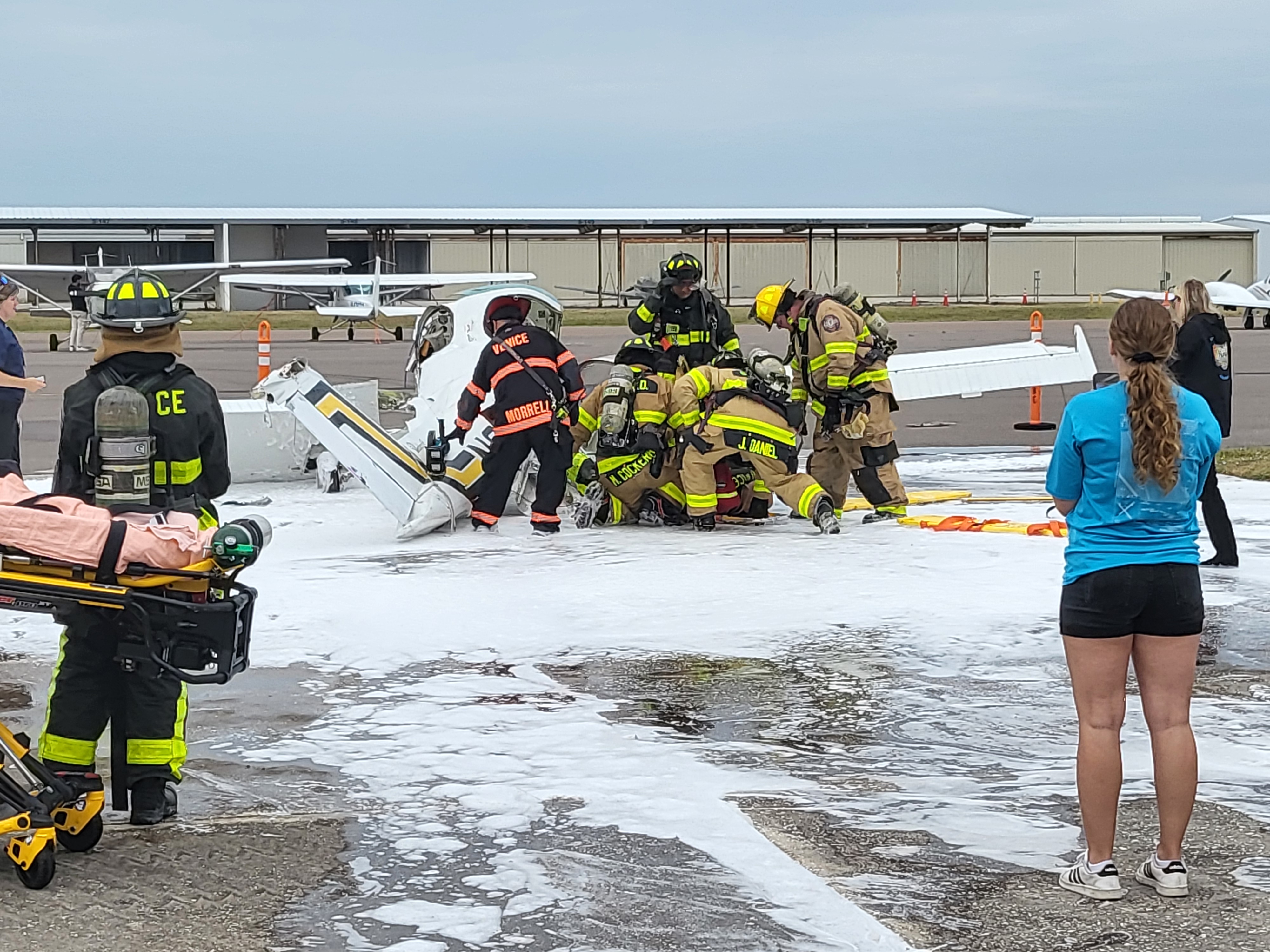 In a later, more complex evolution, responders manage simultaneous hazards and patient care priorities, performing triage using structured systems while stabilizing and securing a patient to a backboard.
