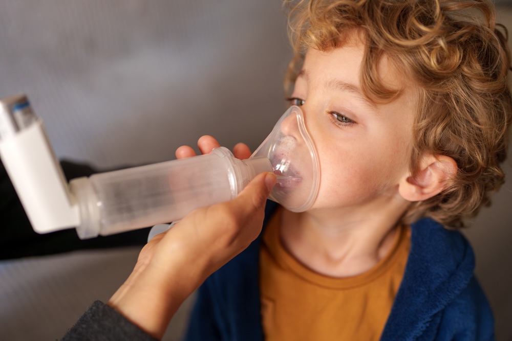 child using inhaler with adult help
