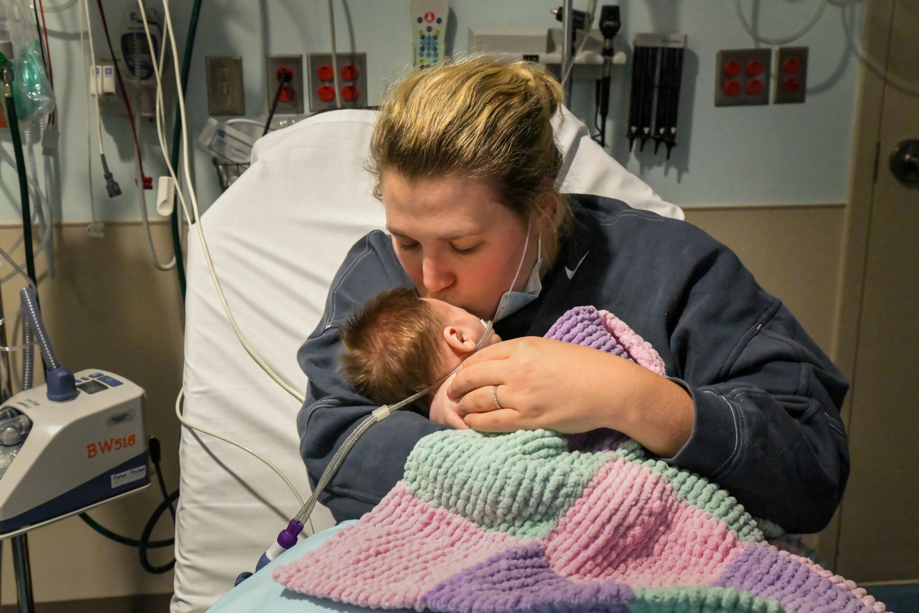 Caitlyn Houston kisses her infant daughter, Parker, as they wait in the emergency department for a hospital bed to open up at Corewell Health Helen DeVos Children's Hospital in Grand Rapids, Michigan, on Dec. 7, 2022. "There's so many kids in here that they have to take the ones that are really bad," Houston says. (Lester Graham/Kaiser Health News/TNS)