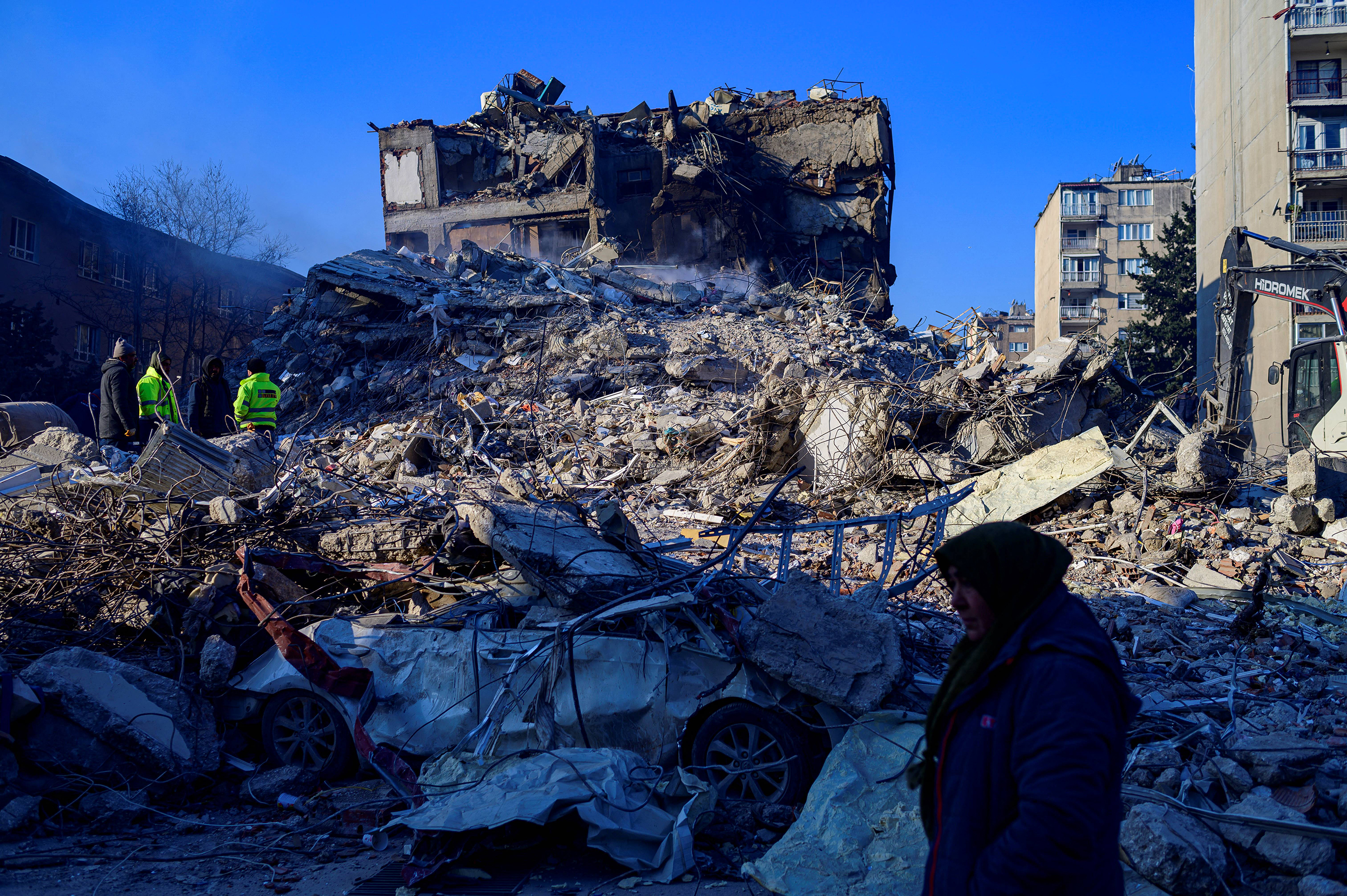 A woman walks by the rubble of a collapsed building in Hatay, on Feb. 10, 2023, four days after the 7.8 magnitude earthquake that killed over 11,200 people. (Yasin Akgul/AFP/Getty Images/TNS)