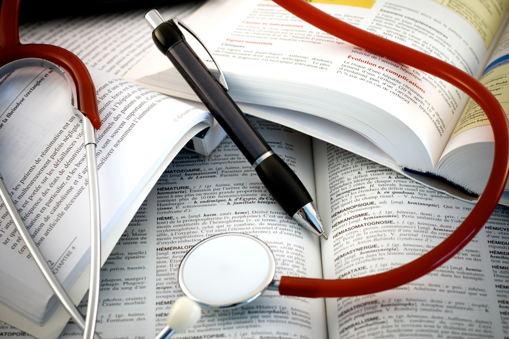 Open medical textbooks with a stethoscope and pen.