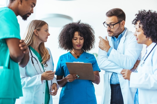 A group of various medical professionals discussing information on a tablet computer