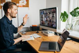 A man speaks to an audience virtually in a conference format via a computer.