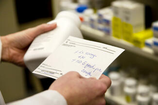 Stock image of a pharmacist holding a prescription and bottle of medication