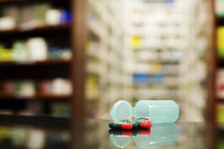 Stock image of an open pill bottle with medication spilling out in a pharmacy.