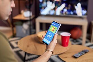 Young man places wager using mobile sports betting app on phone