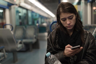 a depressed woman looks at her phone while sitting on a bus, train