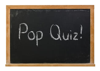 Pop quiz written on a blackboard with white chalk