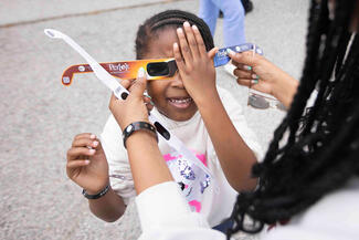 Avery Phillip, 5, of Frisco, Texas, tests her eclipse glasses at the Great North American Eclipse event at the Perot Museum of Nature and Science on Monday, April 8, 2024, in Dallas. This is a historic day for Dallas, which was last in an eclipse's path of totality in 1878, and won't be again for nearly 300 years. (Juan Figueroa/The Dallas Morning News/TNS)