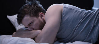 A man lies in bed awake due to insomnia