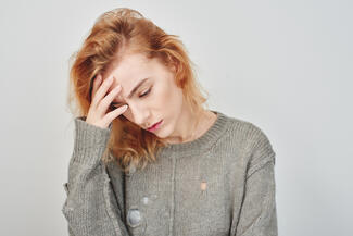 A woman holds her forehead in pain with a migraine