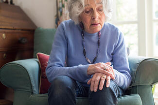 An elderly woman sits on a couch 