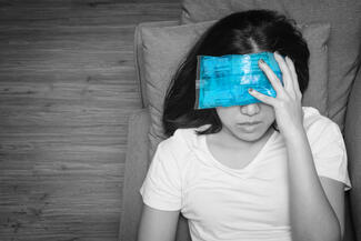 A woman holds her forehead in pain with a migraine