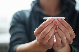 A person holds a cannabis joint in their hands