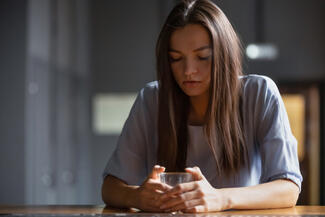 Woman sitting at bar holding a drink.