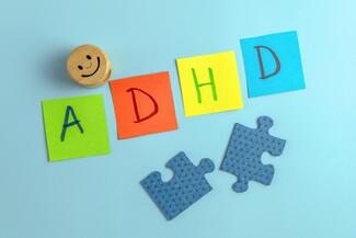 A smily face button, post-it notes with A-D-H-D, and two puzzle pieces