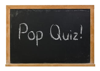 Pop quiz written on a blackboard with white chalk