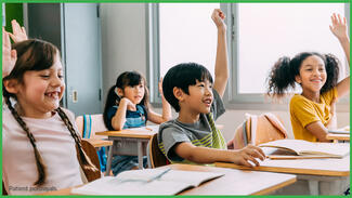 Children in a classroom with some raising their hands