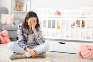 Stressed mother next to crib with baby