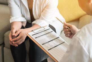 A doctor fills out a form while meeting with a patient