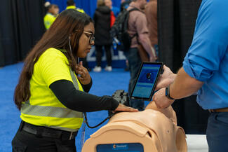 listening to heart and lung sounds on a training dummy at EMS World Expo