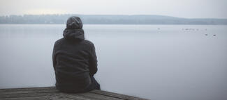 a man sits alone by a lake