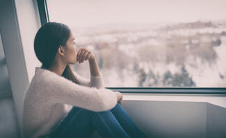 a woman sits on a windowsill and looks out the window