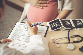 a doctor and pregnant patient sit at a desk