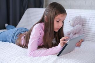 a girl playing a game on a tablet while lying on her stomach