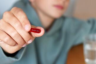 A boy's hand holding a pill that says ADHD