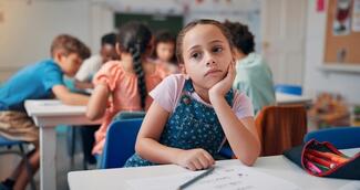 Girl in a classroom staring off into the distance