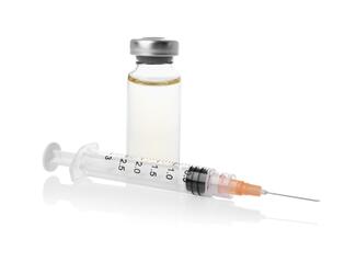 A syringe laying beside an unlabeled medicine bottle filled with clear liquid