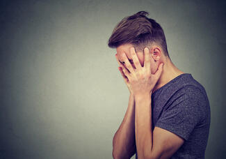 A man with depression holds his head in his hands
