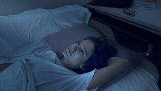 a young woman lies awake in bed