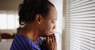a worried woman looks out a window
