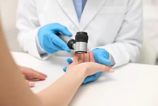 Dermatologist examines patient's palm with dermatoscope