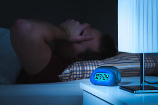 a man unable to sleep and a digital clock displaying 3:24 am