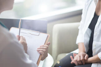 a physician fills out a discharge form while speaking to a patient
