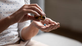a woman pours a pill from a pill bottle into her hand