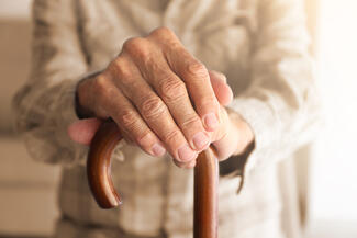 older adult resting hands on cane