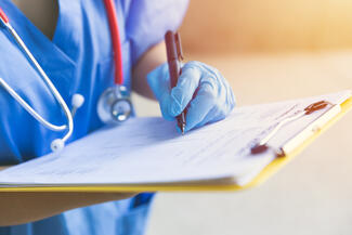 A clinician fills out a form on a clipboard
