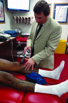 This photo shows Dr. Osterman providing extra-corporeal shock wave therapy (ESWT) for a professional athlete. He shares the significant educational opportunity that exists when working with a multidisciplinary team is a particular reward of the role. Photo courtesy of Howard Osterman, DPM.